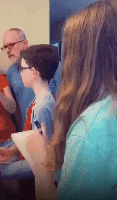 a group of people are sitting around a table and one of them is holding a piece of paper