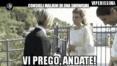 a woman in a white dress is talking to a man in a suit .
