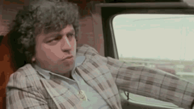 a man is sitting in the driver 's seat of a car .