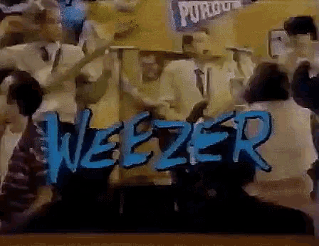 a group of people are gathered around a sign that says weezer