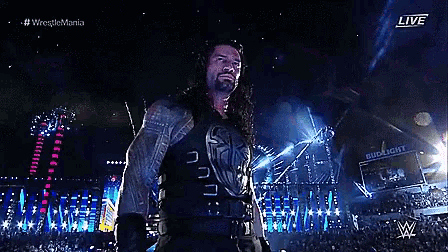 roman reigns is standing in front of a crowd at a wrestlemania live event