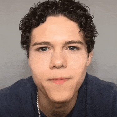 a young man with curly hair looks at the camera