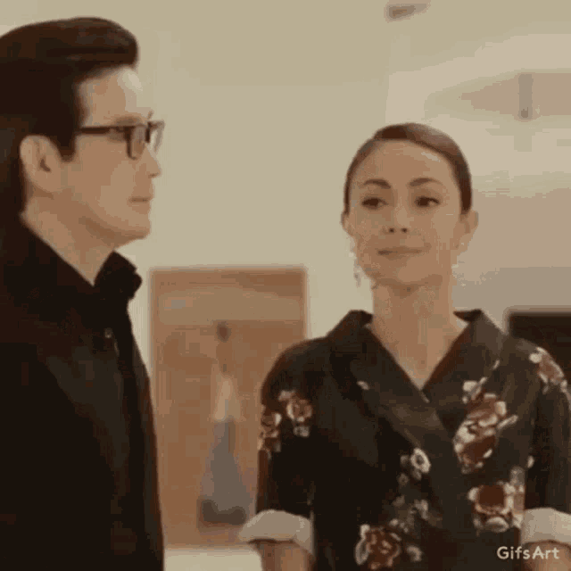 a man and a woman are standing next to each other in a room looking at each other .