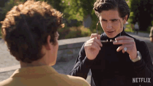 a man wearing glasses is talking to another man with a netflix logo in the background