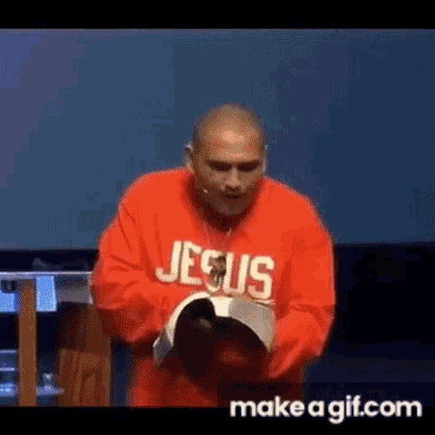 a man wearing a red jesus sweatshirt is holding a bible .