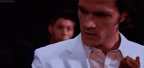 a man in a white suit is holding a red rose in his right hand .
