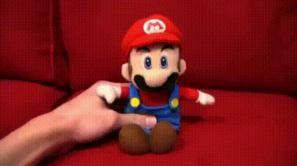 a person is holding a stuffed mario toy on a red couch .