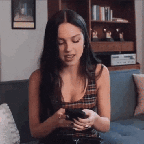 a woman is sitting on a couch looking at her phone