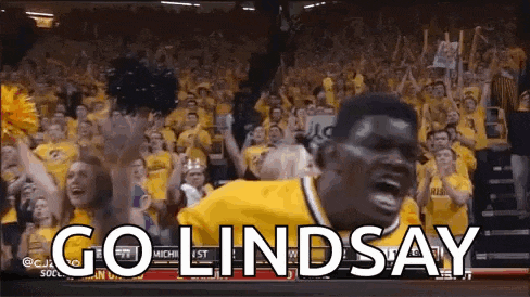 a basketball player is jumping in the air in front of a crowd with the words `` go lindsay '' on the screen .