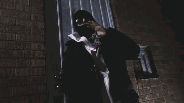 a man wearing a black mask stands in front of a door