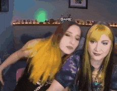 two girls are hugging each other in front of a shelf with the word game on it