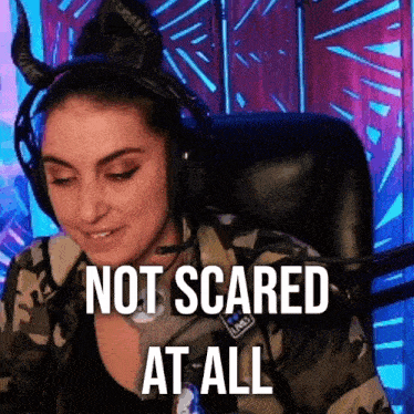 a woman wearing headphones and horns is sitting in a chair and says not scared at all