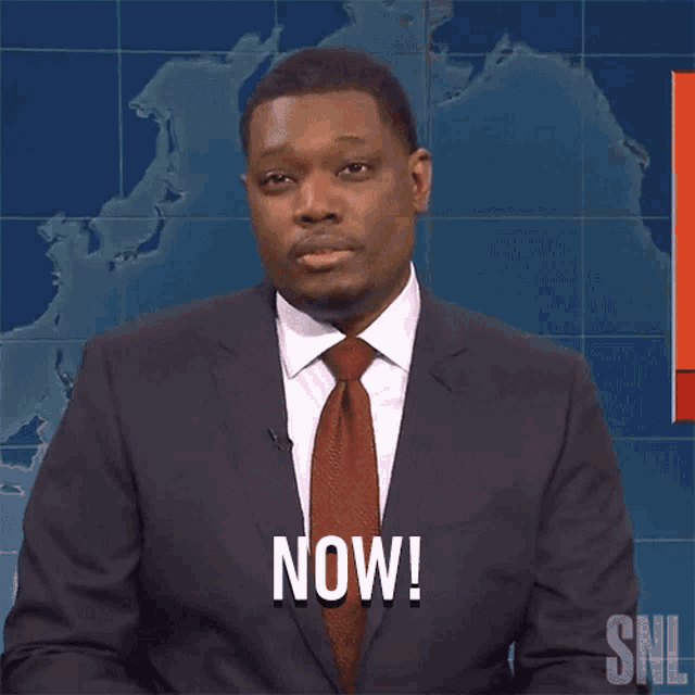 a man in a suit and tie says now in front of a map