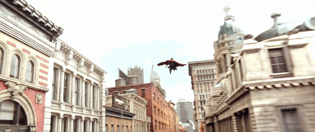 a man in a red cape is flying over a city