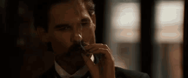 a man in a suit and tie is smoking a cigarette while talking on a phone .
