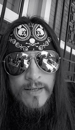a man with a beard wearing sunglasses and a bandana .