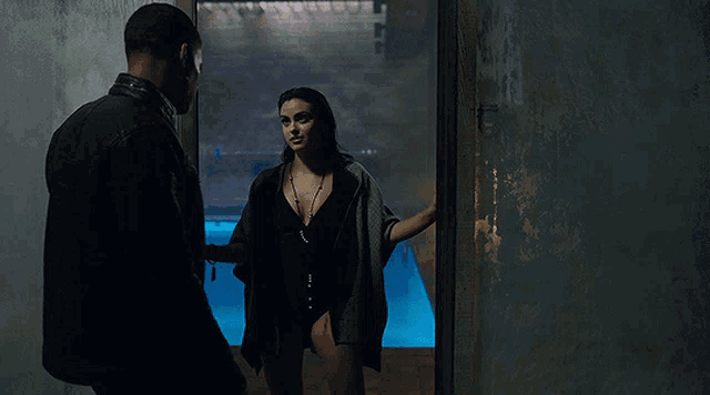 a woman in a bathing suit is standing next to a man in a black jacket