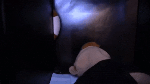 a stuffed animal with big eyes is sitting on a black surface .