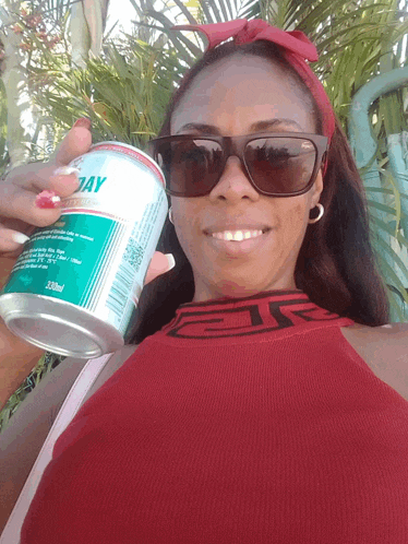 a woman wearing sunglasses is holding a can of sunday beverage