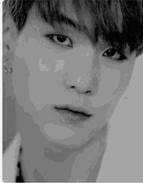 a black and white photo of a young man 's face with a serious look on his face .