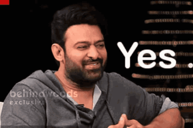 a man with a beard is smiling in front of a sign that says yes