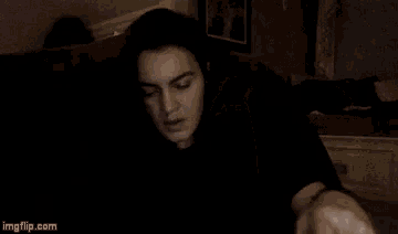 a young woman is sitting on a couch with her eyes closed and her hand on her face .