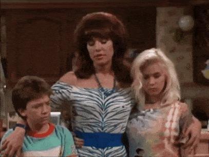 a woman in a zebra print dress is standing next to two other women and a boy .