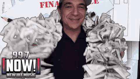 a man is holding a pile of money in front of a sign that reads 997 now