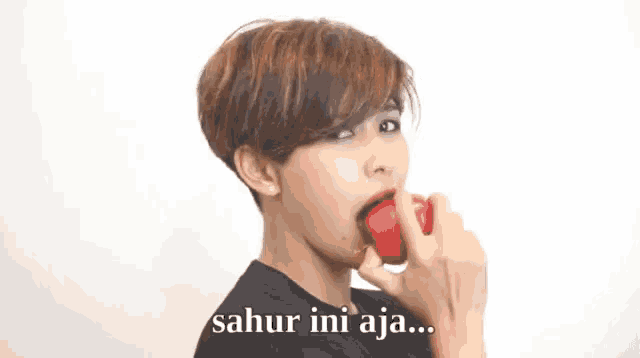 a woman with short hair is holding a red object in her hand and says sahur ini aja .