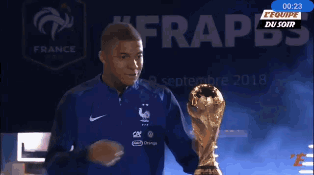 a man is holding a trophy in front of a screen that says france