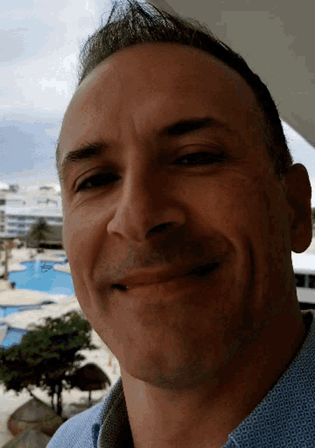 a man in a blue shirt smiles at the camera