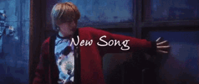 a man in a red sweater is standing in front of a window with the words new song written on it