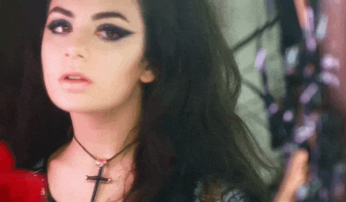 a woman is wearing a choker necklace with a cross on it .