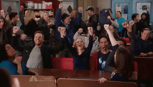 a large group of people are sitting at a table with their fists in the air .