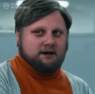 a man with a beard is wearing an orange shirt and a gray sweater .