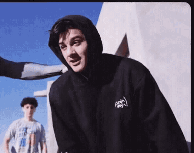 a man in a hoodie is standing next to another man in a t-shirt .