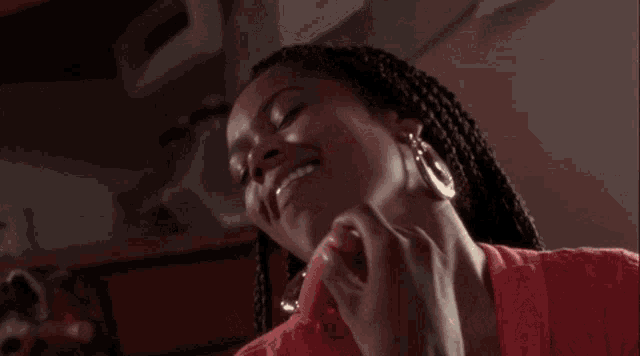 a woman with braids is eating a hot dog .
