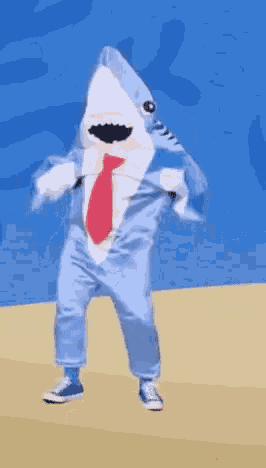 a person in a shark costume is dancing on a beach