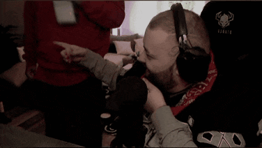 a man wearing headphones and a bandana is kissing another man 's face .