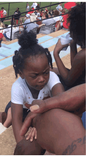 a little girl sitting on a woman 's lap with a cup of water