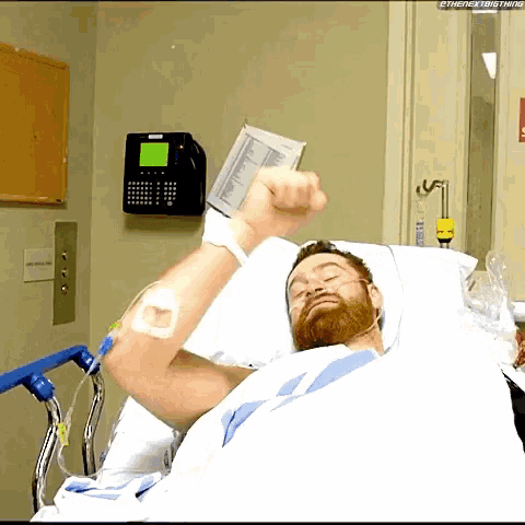 a man is laying in a hospital bed with his fist up in the air