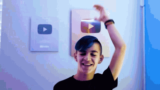 a young man holds up a youtube play button in front of him