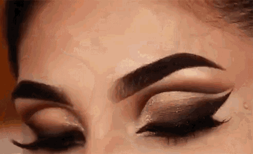 a close up of a woman 's eye with smokey eye makeup and long eyelashes .