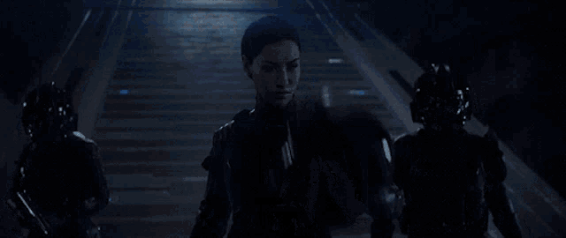 a group of futuristic soldiers are walking down stairs in a dark room .