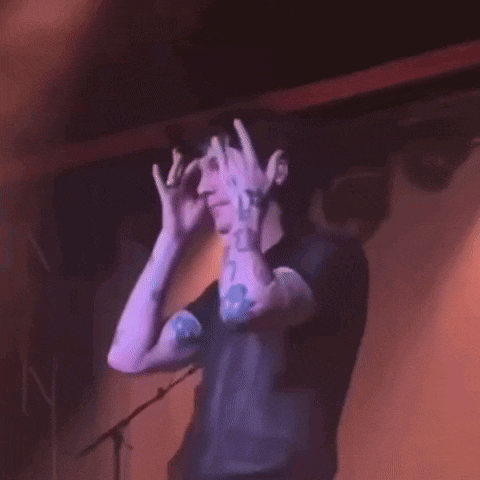 a man with tattoos on his arms is dancing on a stage in front of a microphone .
