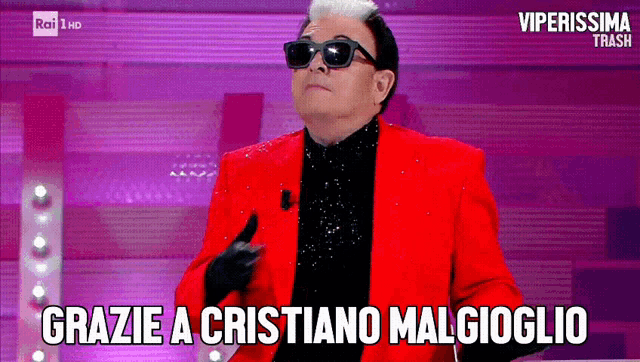 a man in a red jacket and black gloves says grazie a cristiano malgioglio