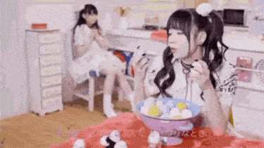 a girl is sitting at a table with a bowl of food and a bowl of eggs .