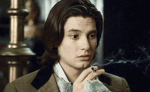 a man in a suit is smoking a cigarette