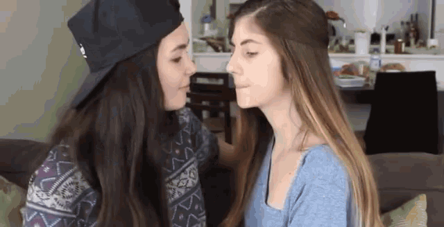 a couple of women are kissing each other in a living room .