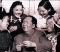 a group of people are posing for a picture with a man holding a cigarette in his hand .